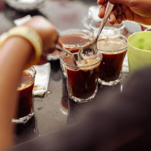 Cropped photo of cup taster man with spoons in hands tasting degustation coffee. Quality test